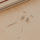 Silver earrings with small gemstones on a beige surface with a book in the background