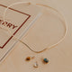 Gold necklace with three pendants on a beige surface
