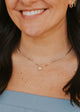 Close-up of a person wearing a delicate gold necklace with a small pendant.