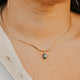 Close-up of a person wearing a gold necklace with a small pendant.