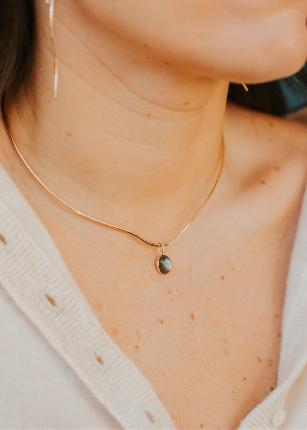 Close-up of a person wearing a gold necklace with a pendant.