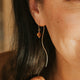 Close-up of a woman wearing gold jewelry including earrings, necklace, and ring.