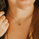 Close-up of a person wearing a gold necklace with a small pendant.