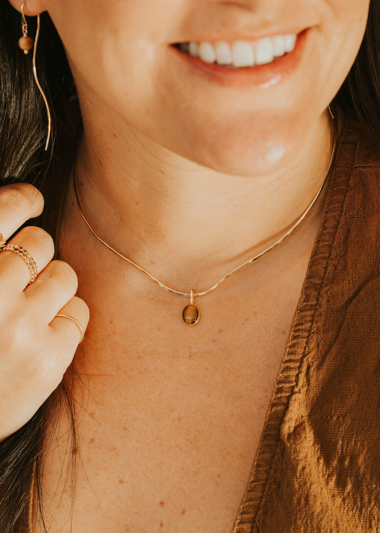 Close-up of a person wearing a gold necklace with a small pendant.