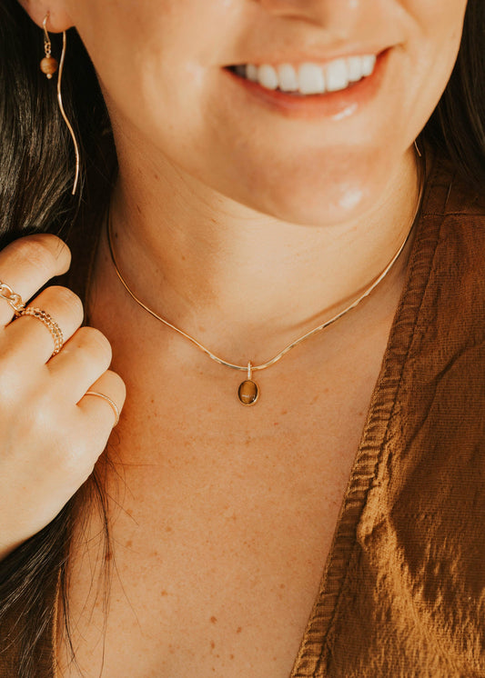 Close-up of a person wearing a gold necklace with a small pendant.