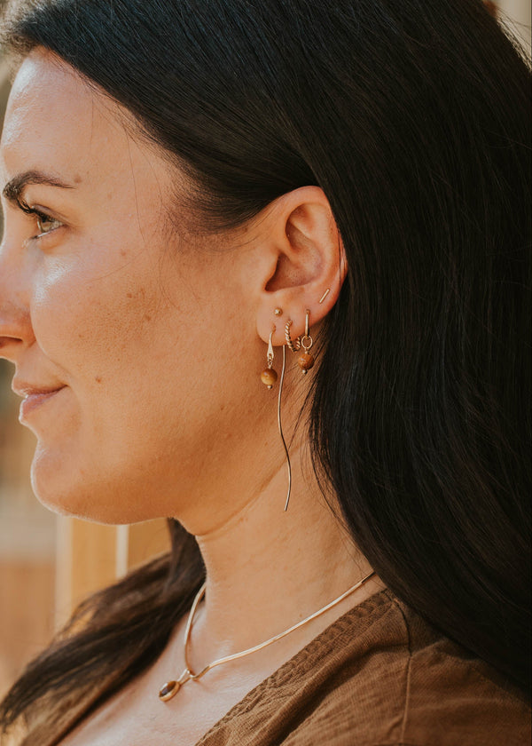 Woman wearing gold earrings and a necklace with a blurred background