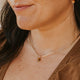 Close-up of a woman wearing gold earrings and a necklace with a blurred background