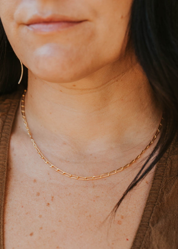 Close-up of a person wearing a gold chain necklace.