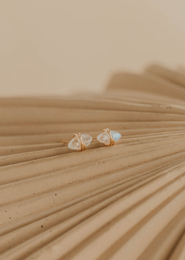 Pair of gold earrings on a textured beige surface