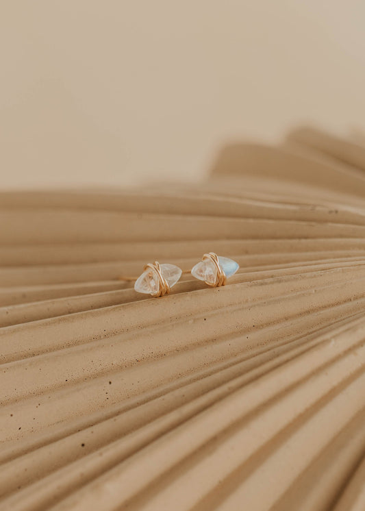 Pair of gold earrings on a textured beige surface