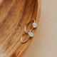 Silver ring with two circular stones on a wooden surface