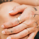 Close-up of a hand with gold rings and tattoos on a blurred background
