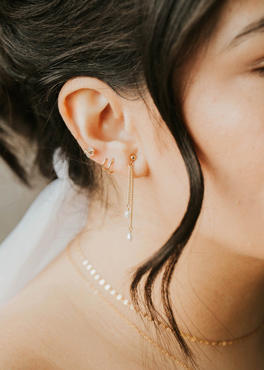 Close-up of a person wearing gold earrings and a delicate necklace.