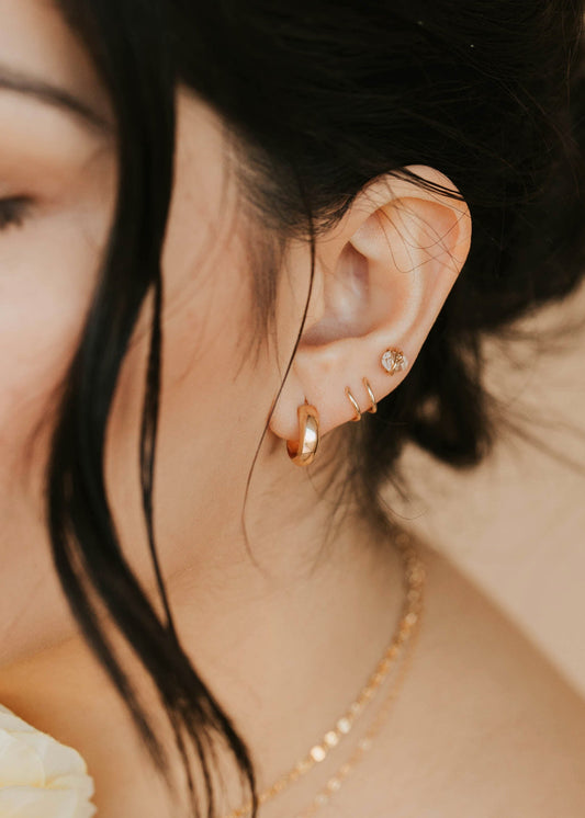Close-up of a person wearing gold earrings and a necklace with a blurred background