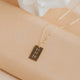 Gold necklace with a bar pendant on a beige surface with a white flower in the background
