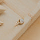 Gold ring with a stone on a textured wooden surface