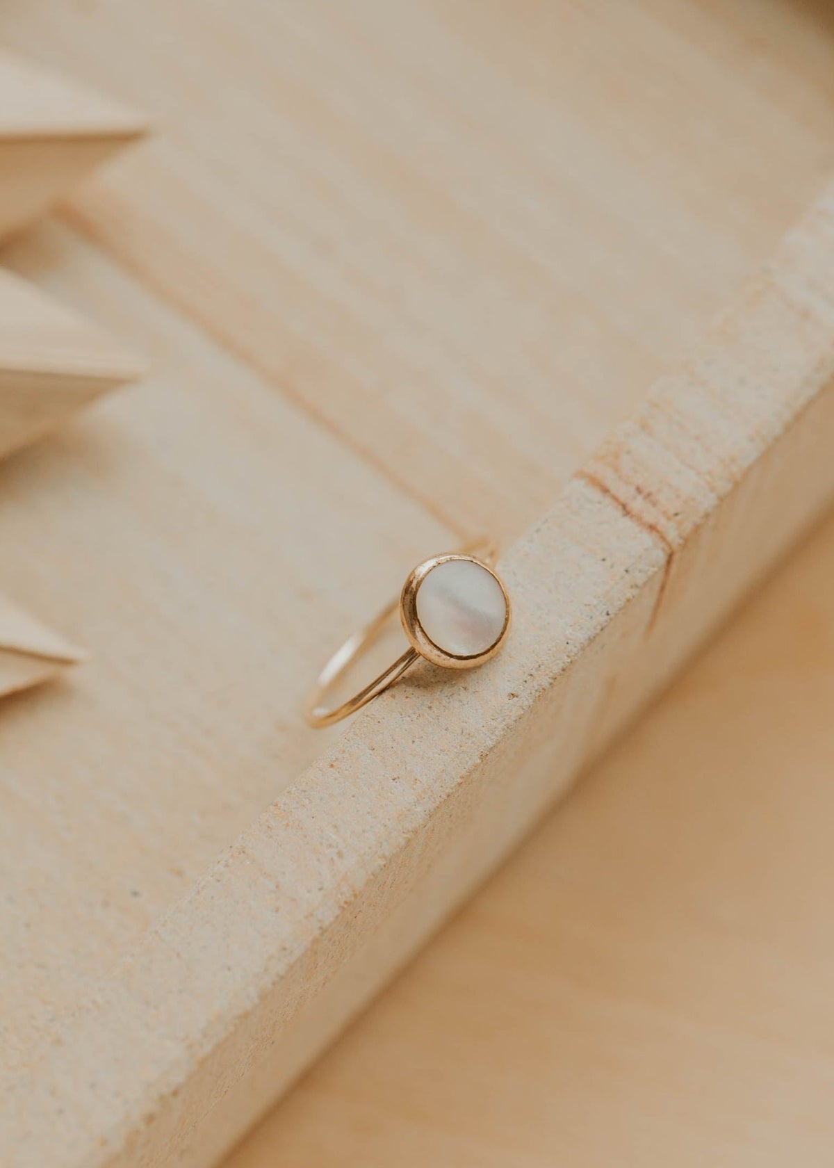 Gold ring with a stone on a textured wooden surface