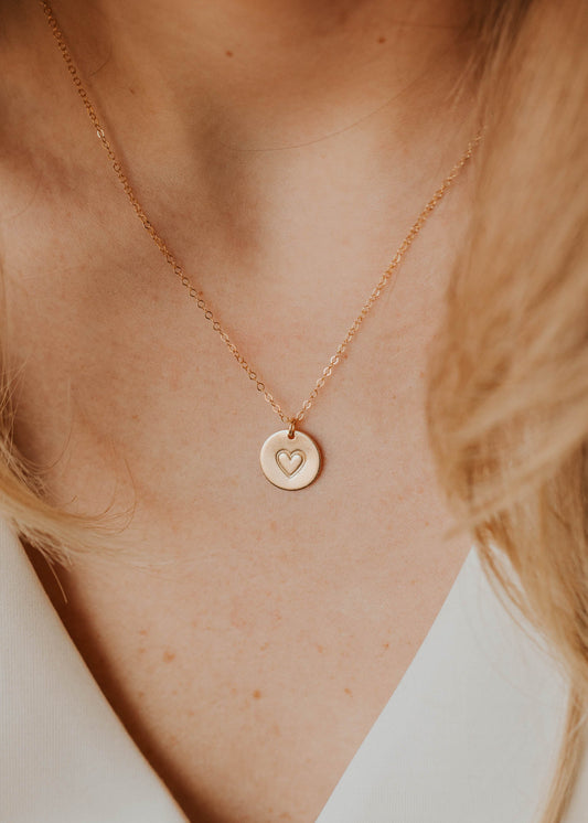 Gold necklace with a heart pendant on a person wearing a white top, proceeds donated to HeartWorks.