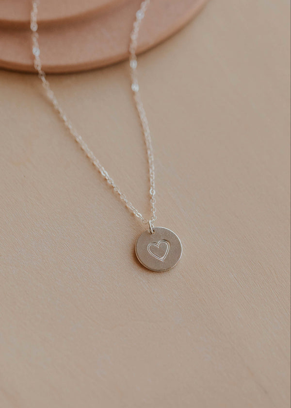 Necklace with a heart pendant on a beige surface