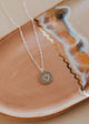 Silver necklace with a heart pendant on a ceramic plate