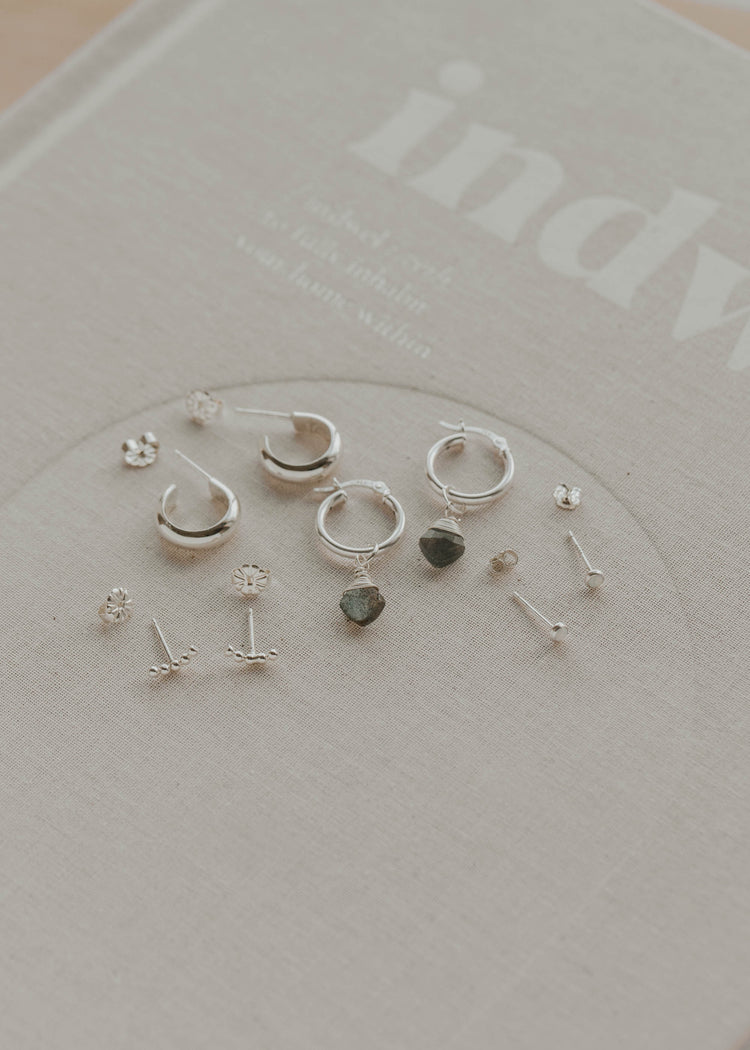 Collection of silver earrings on a branded card