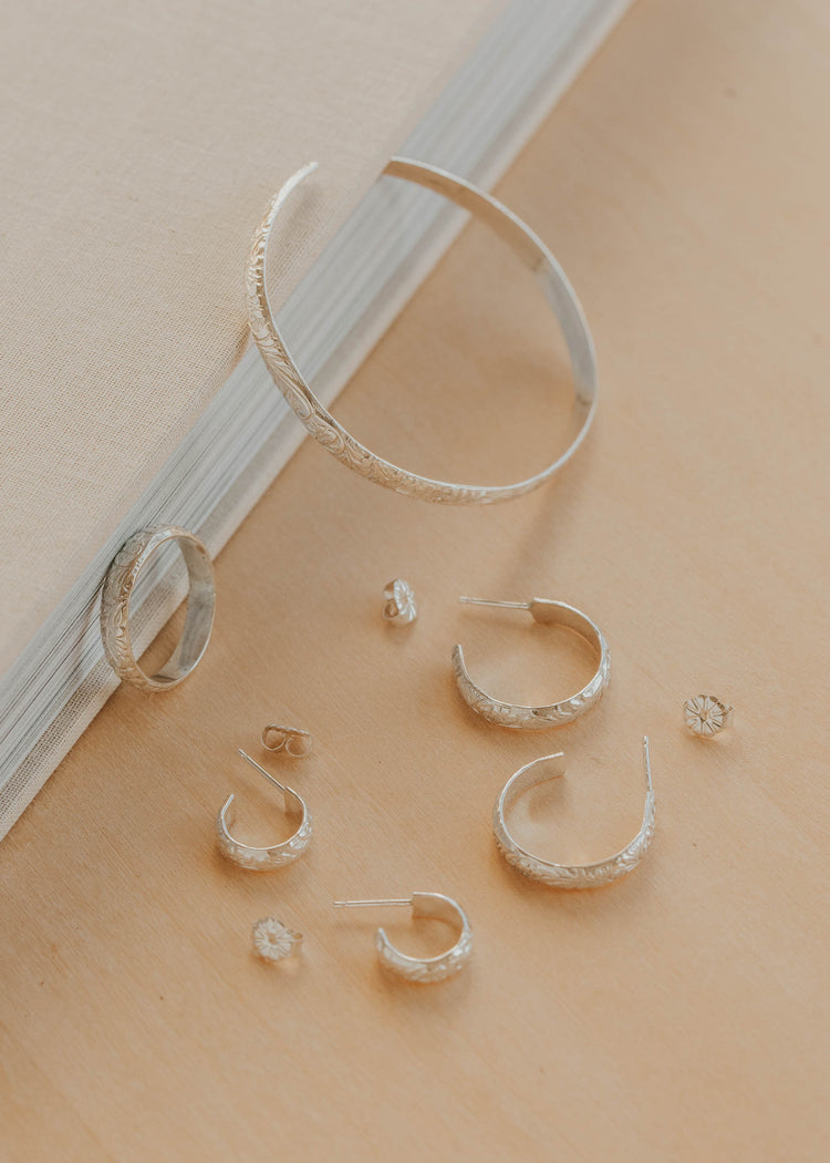 Silver hoop earrings on a beige surface