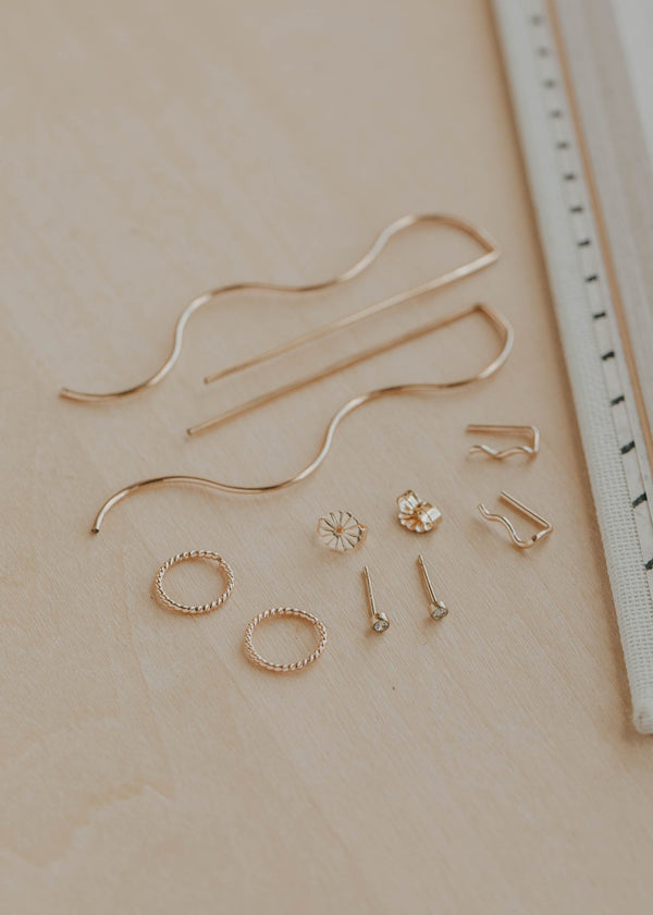Set of gold jewelry pieces on a beige surface with a ruler for scale.