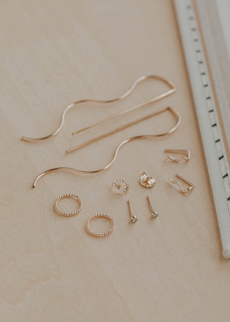 Set of gold jewelry pieces on a beige surface with a ruler for scale.