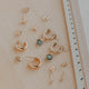 Collection of gold earrings on a light surface with a ruler for scale.