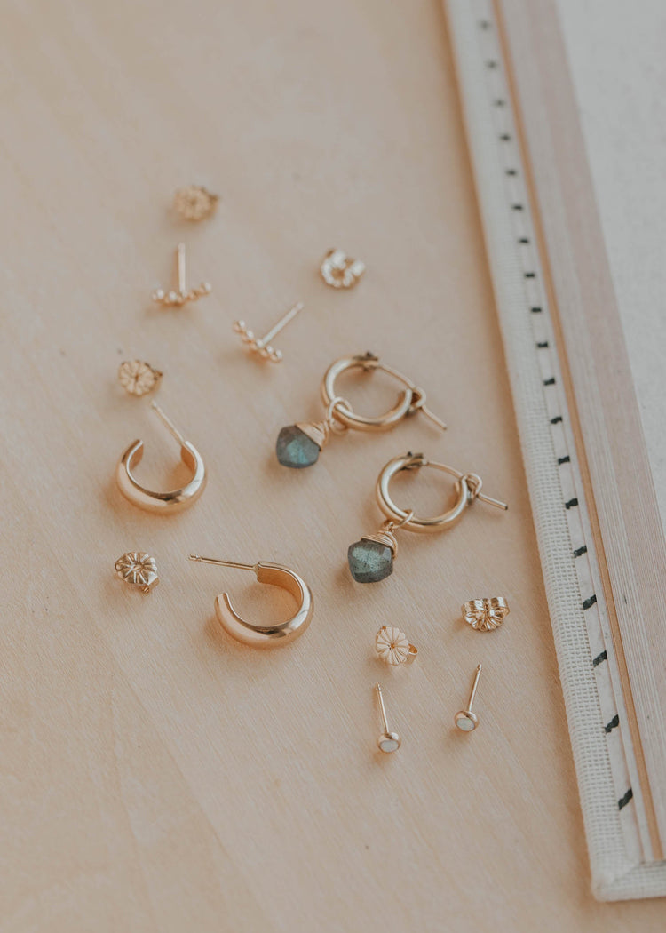 Collection of gold earrings on a light surface with a ruler for scale.