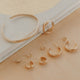 Set of gold hoop earrings on a beige surface with a white cloth