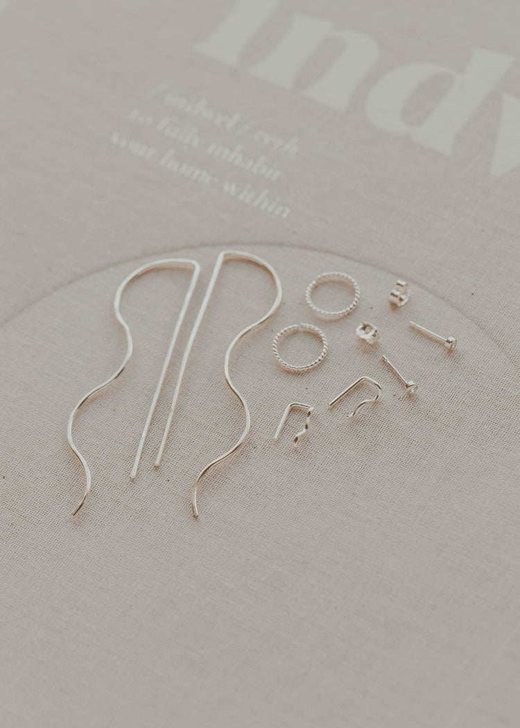 Gold earring hooks on a light gray background with 'indy' branding.