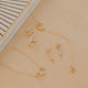 Gold jewelry set including necklaces and earrings on a beige surface with a striped fabric background.