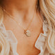 Close-up of a person wearing a delicate gold necklace with a round pendant.