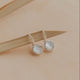 Pair of silver earrings with round gemstones on a beige background