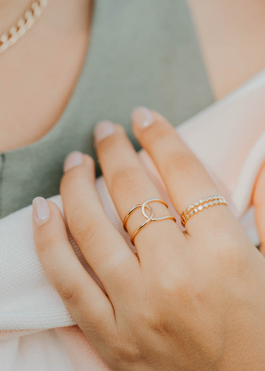 Close-up of a hand wearing two gold rings with a blurred background