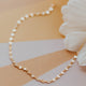 Pearl and gold chain necklace on a striped background with flowers
