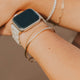 Person wearing a smartwatch with multiple bracelets on a blurred background
