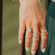 Close-up of a hand with multiple rings and bracelets against a blurred background