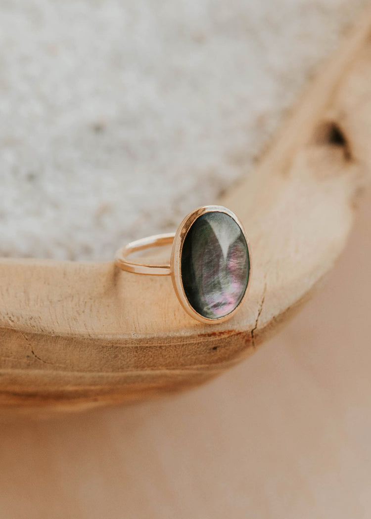 Gold ring with a green stone on a wooden surface