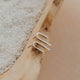Silver ear cuff on a wooden surface with sand in the background