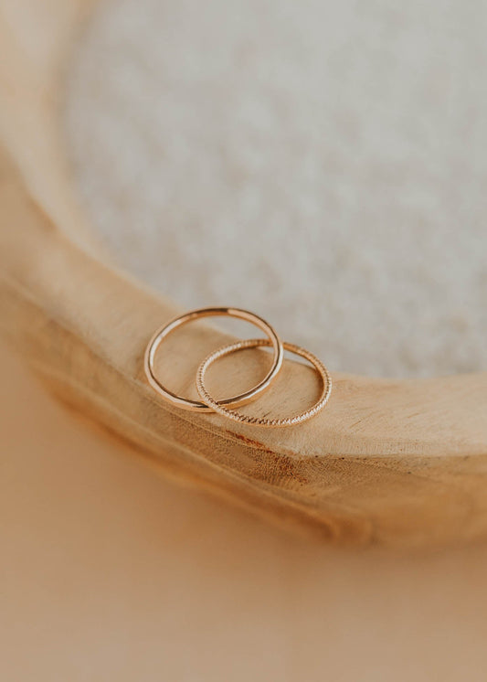 Two gold rings on a wooden surface with a soft focus background