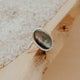 Silver ring with a green stone on a wooden surface