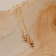 Gold earrings with beaded pendant on a wooden surface