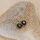 Silver earrings with gemstones on a textured stone surface