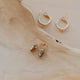 Gold hoop earrings on a wooden surface