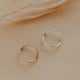 Two gold rings on a beige surface with dried grass.