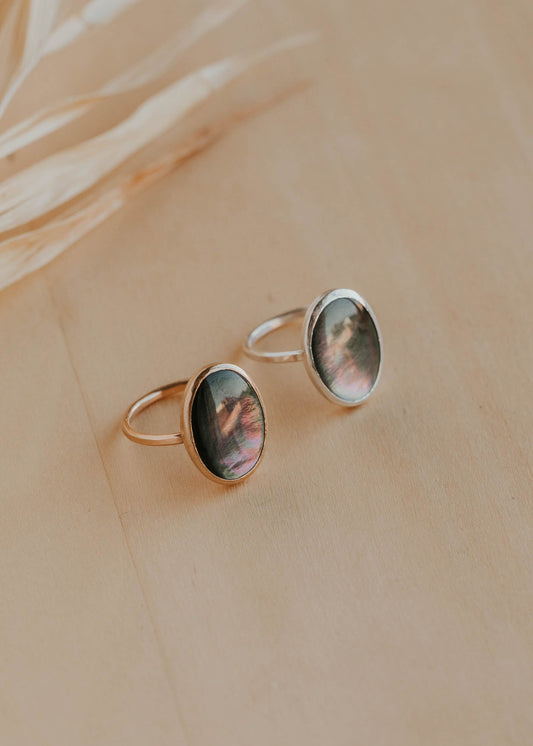 Two gold rings with circular gemstones on a beige background