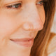 Close-up of a person wearing a Hello Adorn gold nose ring with a blurred background