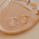 Gold and silver heart-shaped rings on a beige ceramic dish with a marble pattern.